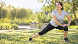Mujer sonriendo haciendo una estocada lateral al aire libre, ejercicio para cuidar la firmeza de los muslos
